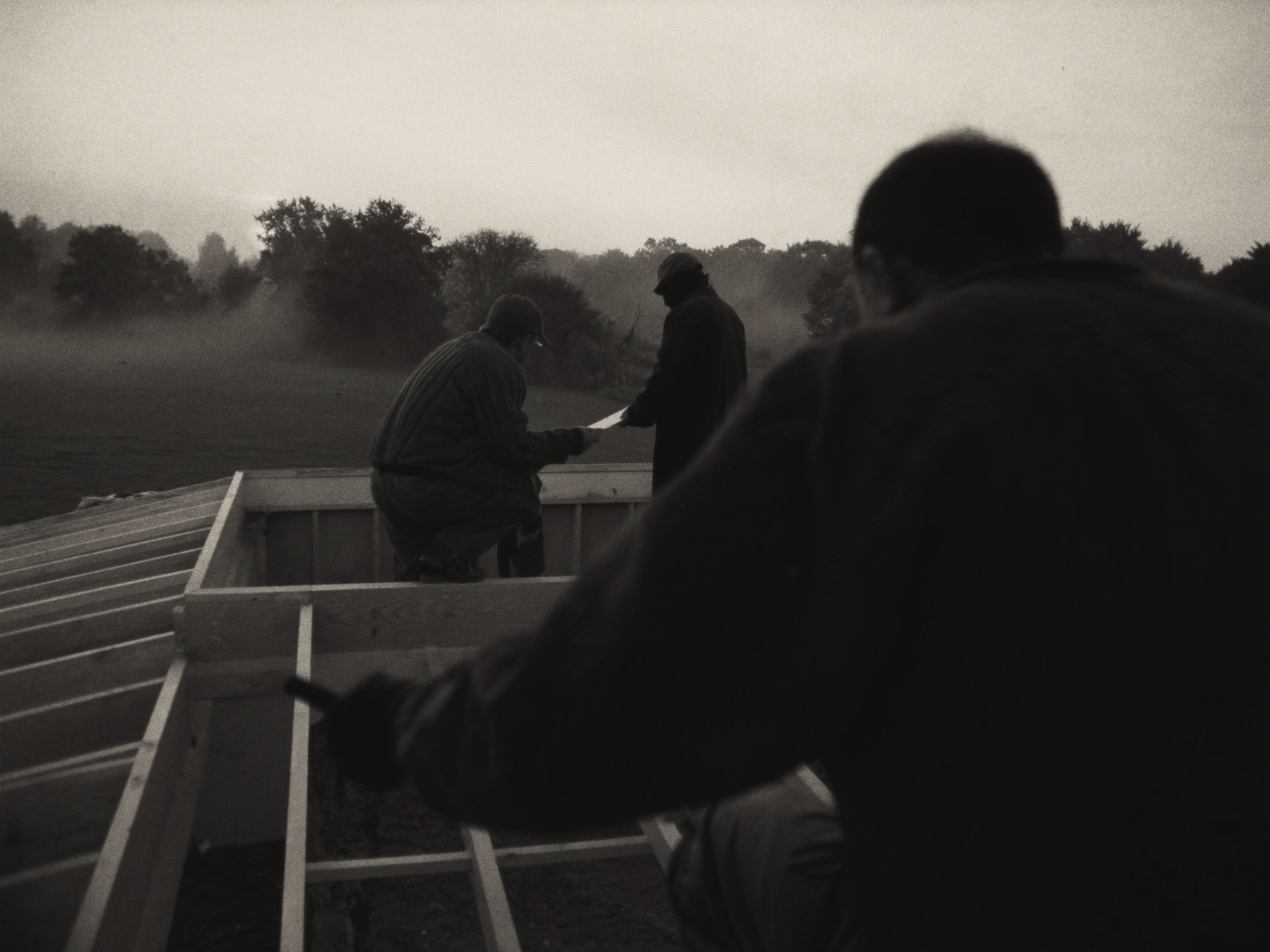 Framing crew on the roof of a custom home with morning mist